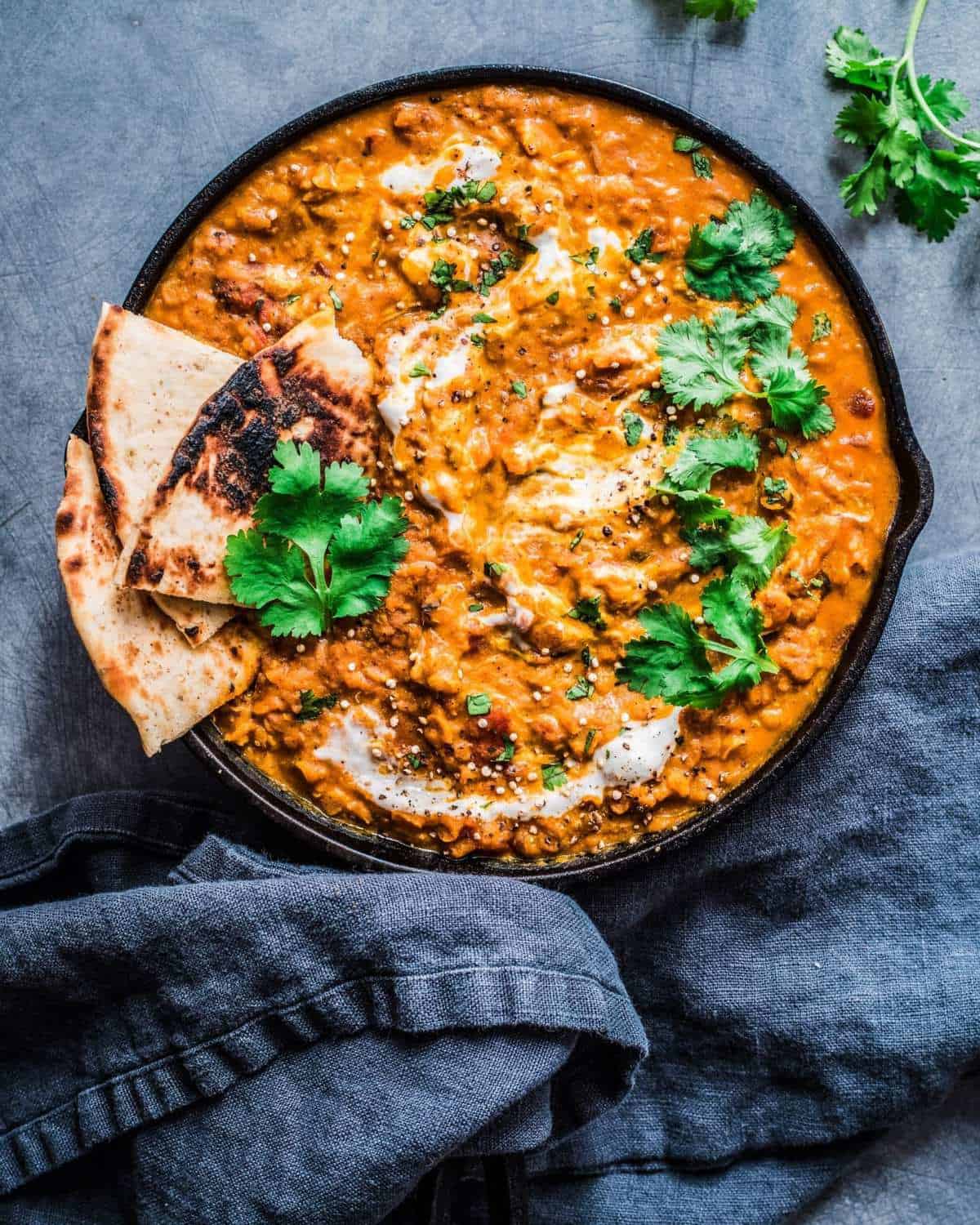 overhead shot of red lentil curry next to blue napkin