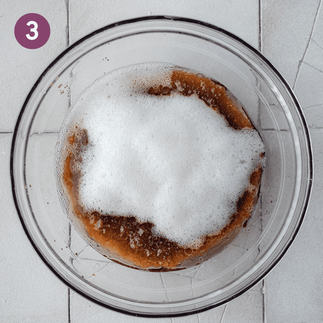 foamy aquafaba sitting on top of brown sugar mixed with oil in glass bowl.