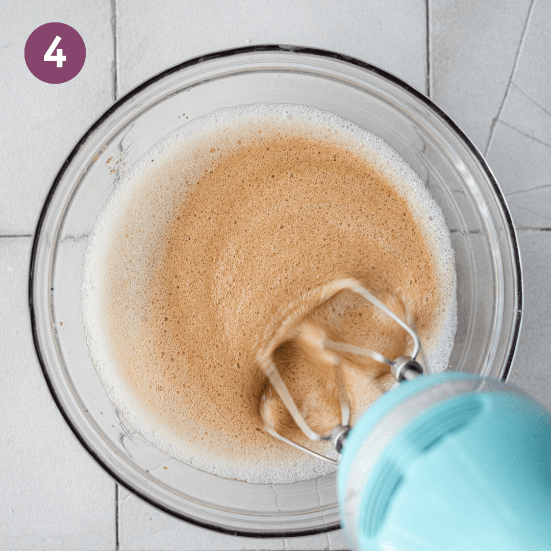 hand mixer beating liquid ingredients for pumpkin bread in a glass bowl.