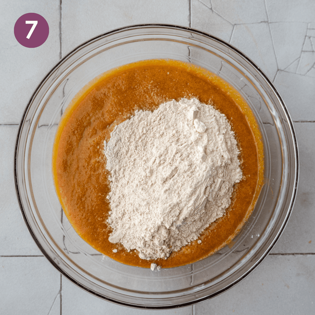 dry ingredients sitting on top of liquid ingredients for vegan pumpkin bread in a glass bowl.