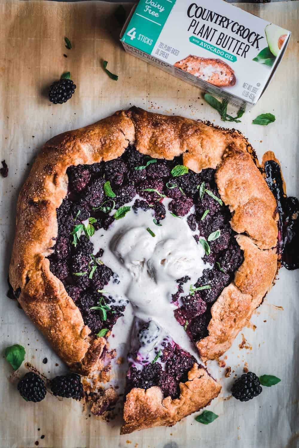 Cooked blackberry galette with mint, basil and vegan ice cream on a baking sheet.