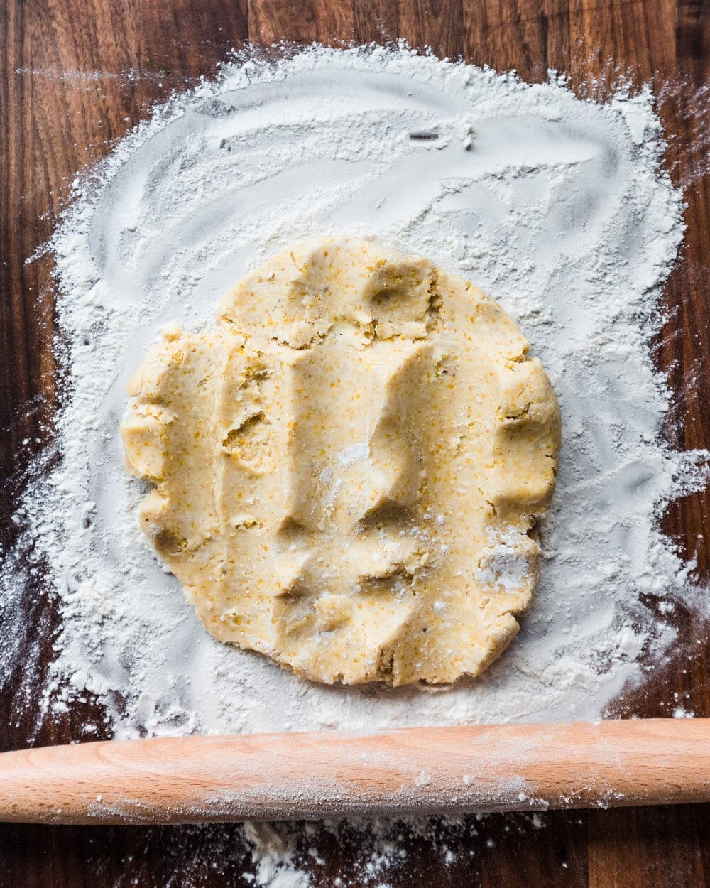 Dough partially flattened on a floured work surface by the rolling pin.