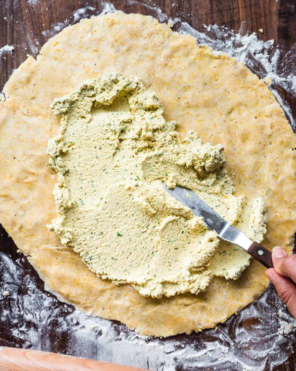 Person starting to spread the tofu ricotta on the galette dough.