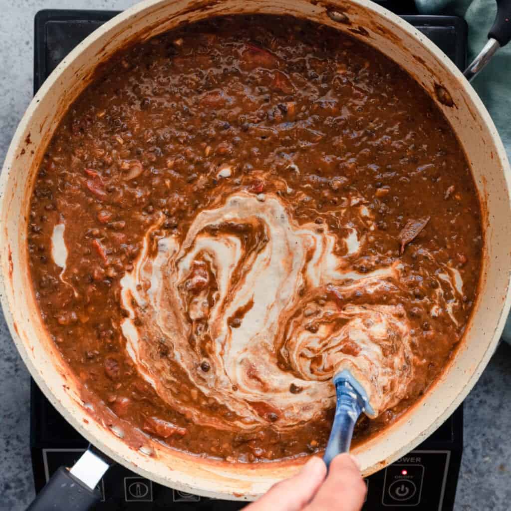 stirring cashew cream into vegan dal makhani
