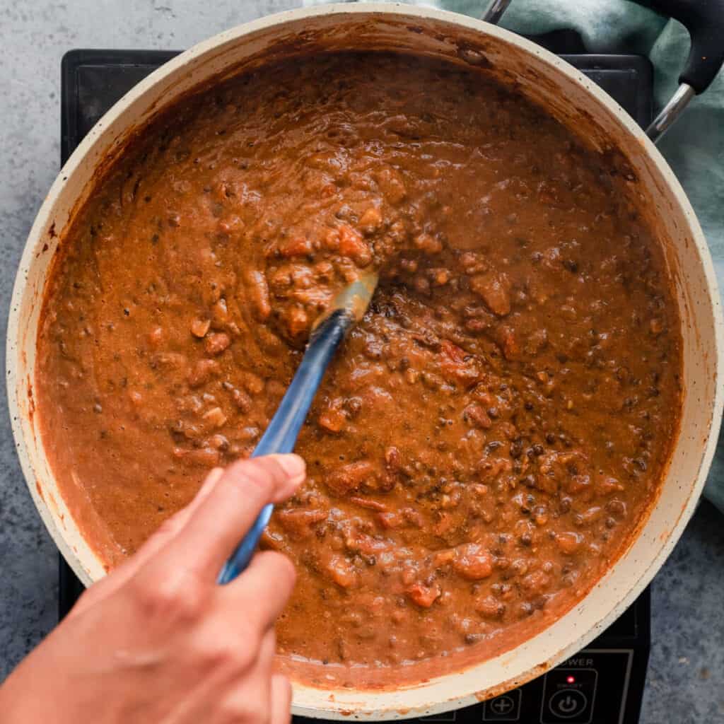 stirring a creamy pan of vegan dal makhani