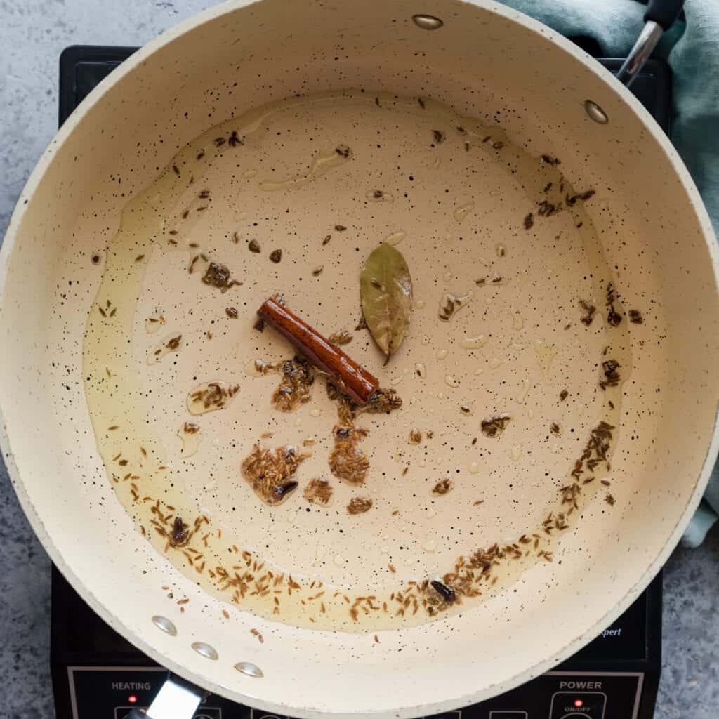 cooking whole spices in oil in a frying pan