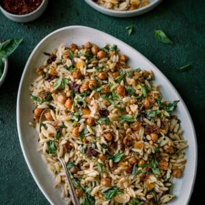 lemon orzo pasta salad on white tray on dark green backdrop