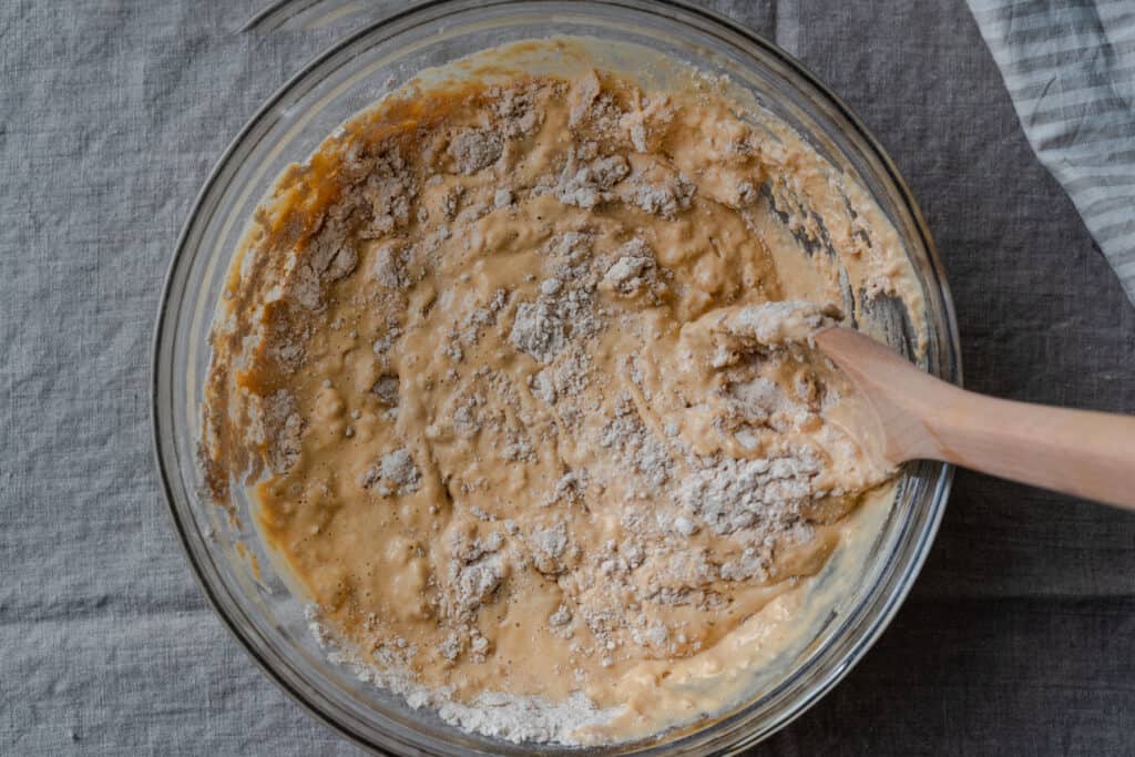 wooden spoon mixing liquid ingredients into dry ingredients