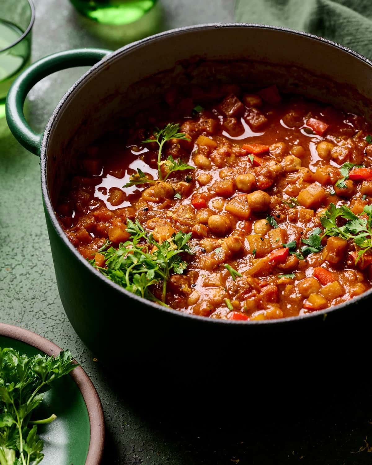 Side view of dutch oven filled with tagine on a green table.
