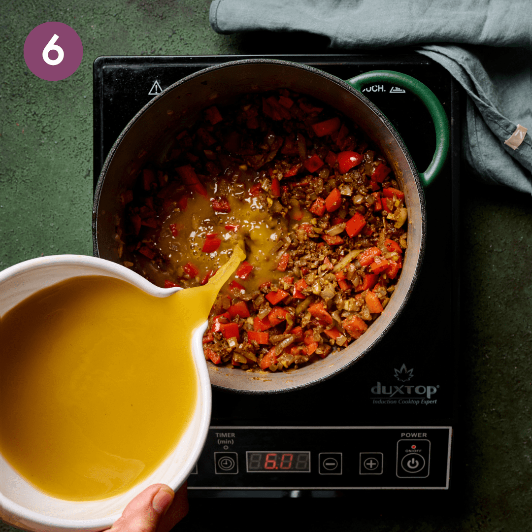 Person pouring vegetable broth into the pot.