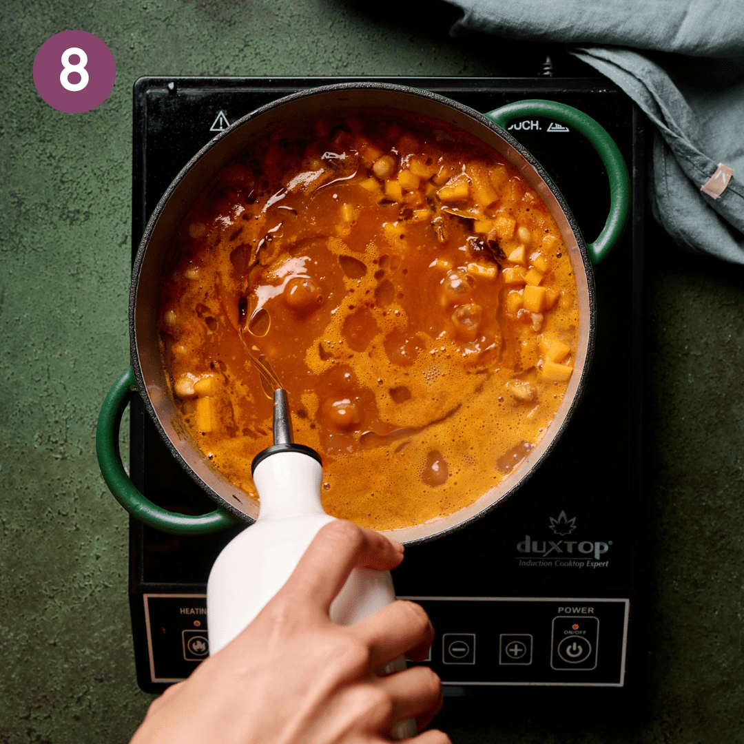 Person stirring the pot after a glug of olive oil is added.