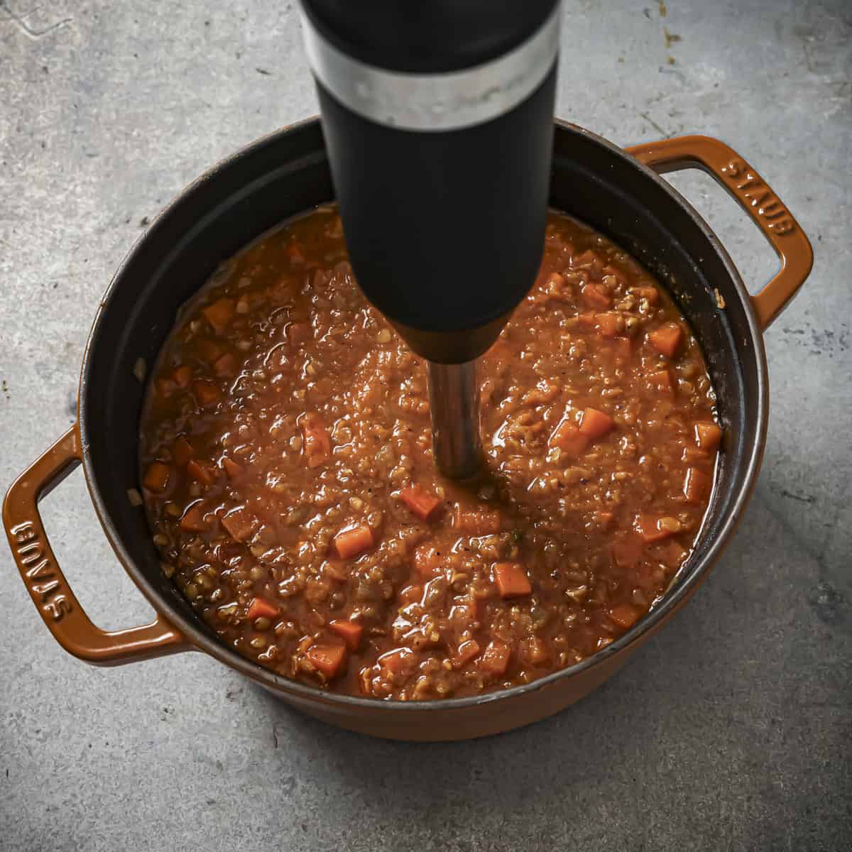Immersion blender in the pot blending up half the soup.