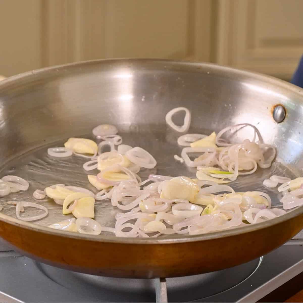Shallots and garlic in a frying pan with oil.
